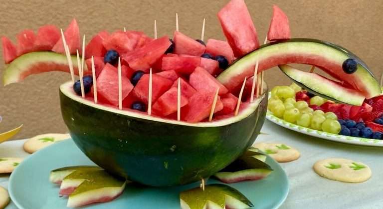eine Wassermelone aufgeschnitten und als Dinosaurier geschnitzt mit Wassermelonen Stücken drinnen für das Geburtstags-Buffet