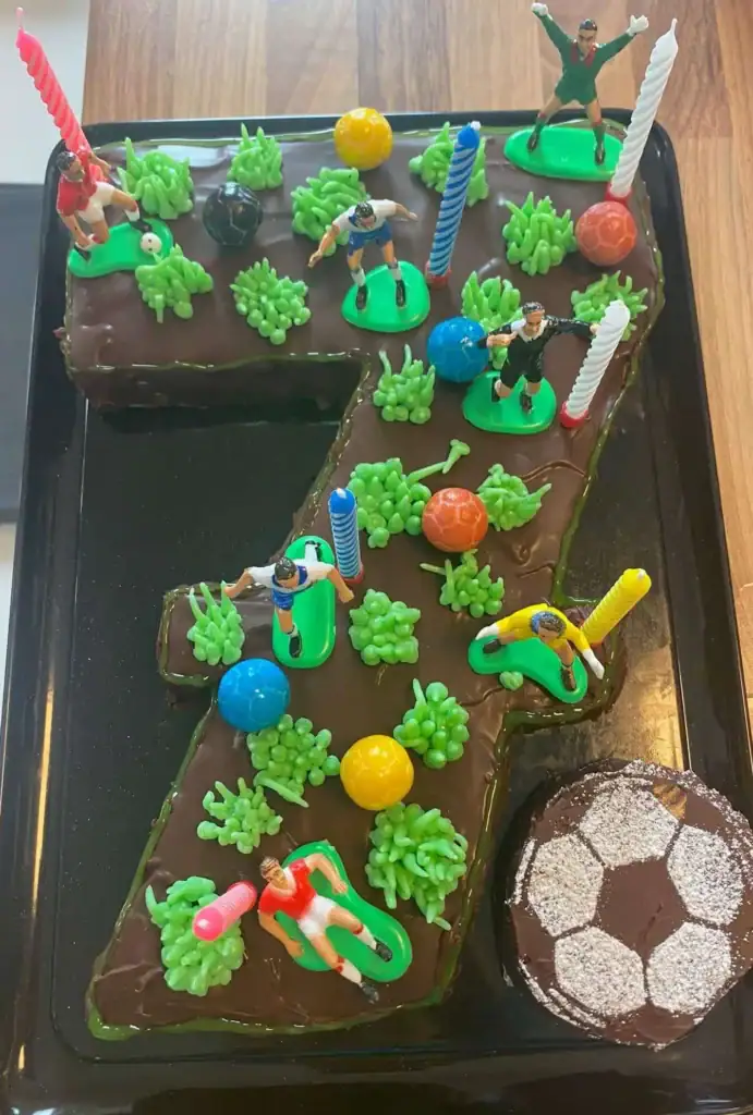 Zahlentorte 7 als Fußballfeld mit Fußballern und Fußbällen und Gras mit Buttercreme aufgespritzt