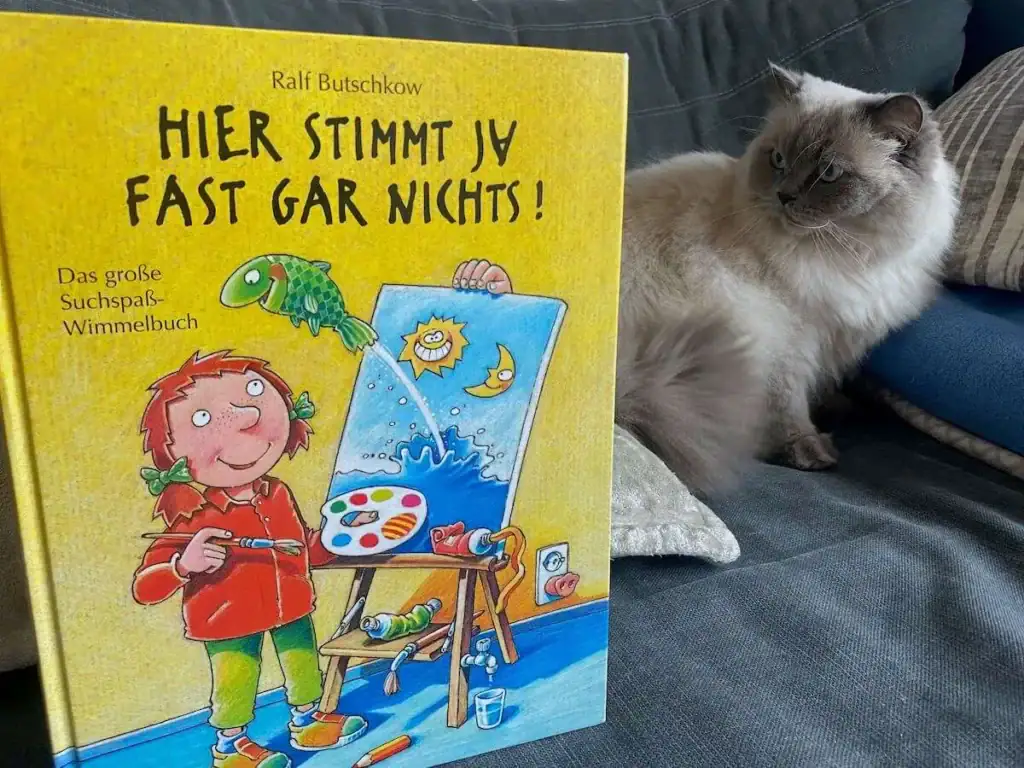 Kinderbuch-Tipp des Monats - Hier stimmt ja fast gar nichts - steht auf der Couch und die katze sitzt daneben und schaut es an