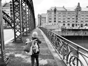 Kind geht auf einer Brücke mit dem Rücken zum Foto Richtung Speicherstadtmuseum