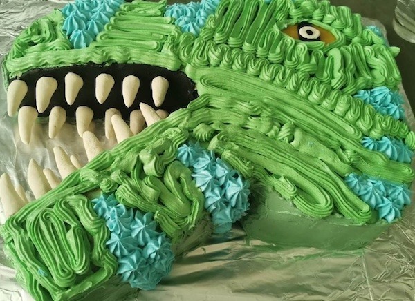 Kuchen in Dinoform als Kopf mit grüner Buttercreme