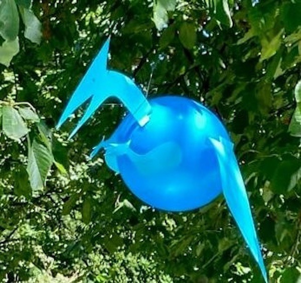 blauer Luftballon als Dino dekoriert hängt an einem Baum