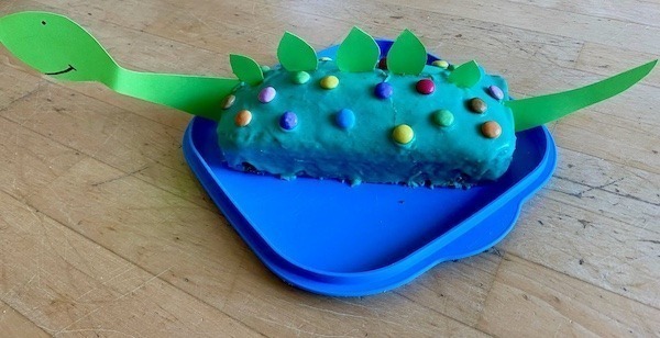 Zitronenkuchen in Kastenform mit Kartonteilen zu einem Dino verwandelt