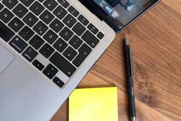 computertastatur mit Notizblock und stift
