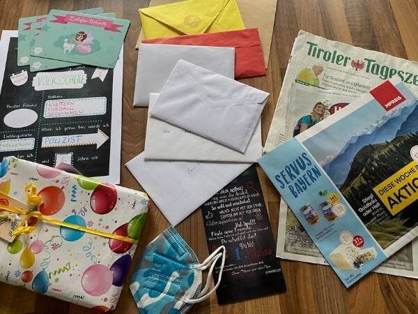 Inhalt unserer Zeitkapsel auf einem Tisch aufgelegt. Von der Tageszeitung bis zum Werbeprospekt, Briefe, Karten der Zahnfee und mehr