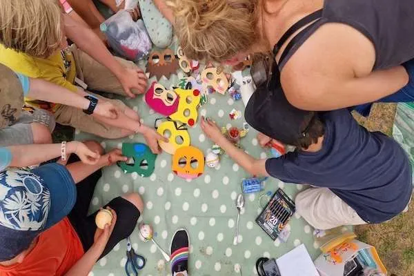 Basteldinge am Boden, rundherum viele kinder, sie sich etwas aussuchen