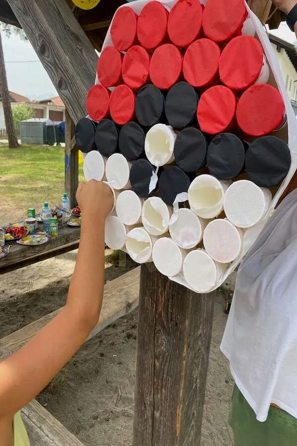 Pokeball aus Bechern, wie eine Hand gerade das Seidenpapier durchschlägt