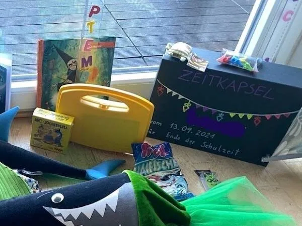 Zeitkapsel umrahmt von andere Geschenken zur Einschulung