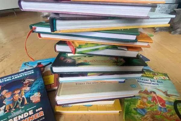 unsere 30+ Kinderbücher auf einem Stapel am Boden