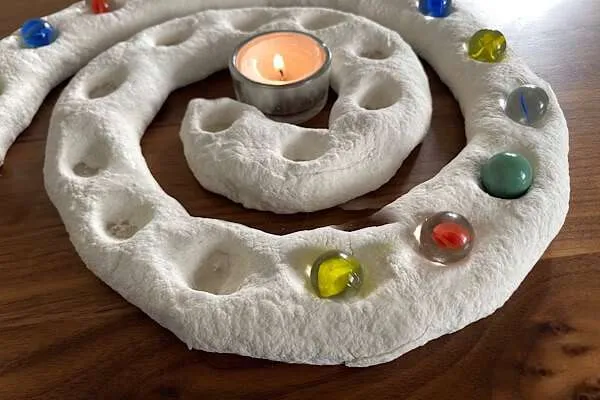 Adventsspirale mit murmeln und einer Kerze in der Mitte