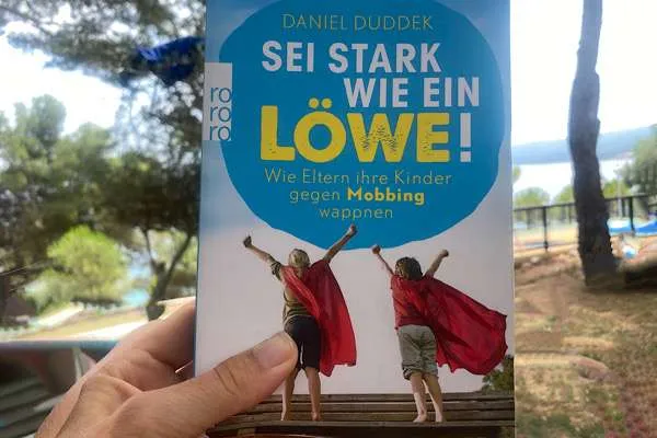 Buchcover für Hilfe bei Mobbing von "Sei stark wie ein Löwe" im Hintergrund Landschaft