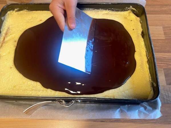 H&auml;nde gie&szlig;en geschmolzene Schokolade auf selbstgemachten Kuchen in Backform, perfekte Torten-Deko f&uuml;r Backliebe und Genuss.