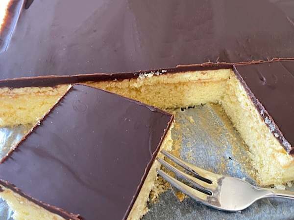 Ein St&uuml;ck k&ouml;stlicher Puddingkuchen mit Schokoladenglasur, perfekt f&uuml;r Geburtstage und Feste, dekoriert mit gl&auml;nzender Schokoladenschicht.