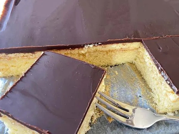 Ein Stück köstliche Puddingkuchen mit Schokoladenglasur, perfekt für Geburtstage und Feste, dekoriert mit glänzender Schokoladenschicht.