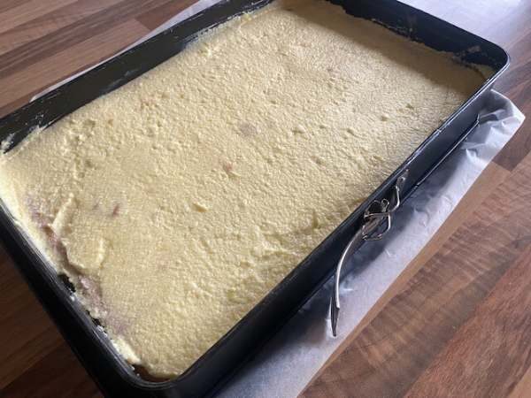 Fertig gebackener Kuchenboden in rechteckiger Backform, gleichm&auml;&szlig;ig mit Puddingcreme bestrichen.
