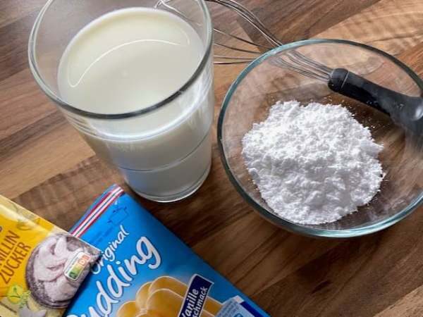 Milch, Vanillepuddingpulver, Butter und Puderzucker als Zutaten f&uuml;r die Puddingcreme.