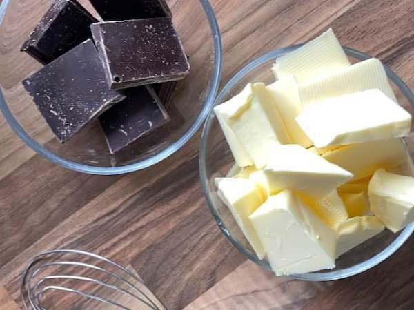Hochwertige Schokolade und Butter f&uuml;r Backrezepte auf einem Holzbrett.