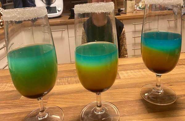 3 Rainbow Kindercocktail mit Zuckerrand auf einem Tisch 