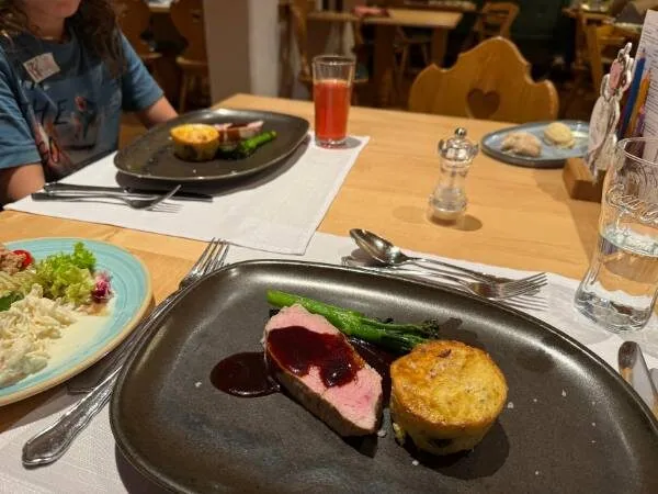 Ein köstliches Steak mit Soße, Kartoffelauflauf und grünem Spargel auf einem schwarzen Teller, serviert in einem gemütlichen Restaurant, perfekt für Gourmet-Momente.