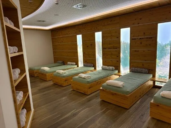 Entspannungsraum im Spa mit Liegen und Panoramablick, Holzinterieur und Ruhezone für Erholung.