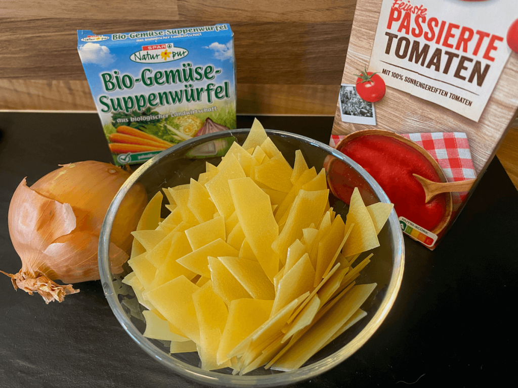 Zutaten für die Lasagenesuppe: Lasagneplatten in Stücke gebrochen, passierte Tomaten, Zwiebel, Suppenwürfel