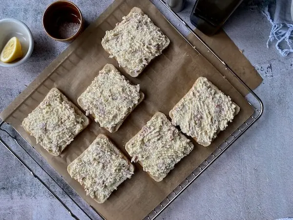 Flammkuchentoast vor dem Überbacken auf einem Rost mit Backpapier