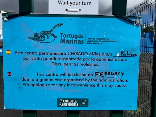 Schild am Turtle Rescue Center auf Fuerteventura mit Informationen zur vor&uuml;bergehenden Schlie&szlig;ung im Februar, inklusive Hinweise in Deutsch und Englisch.