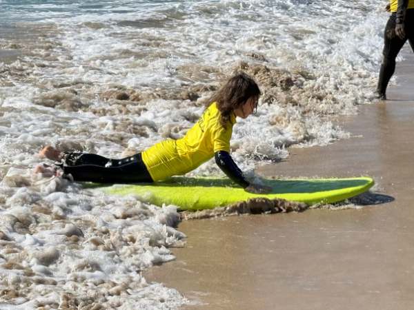 Frau beim Surfen mit Kind am Strand von Fuerteventura, Familienurlaub mit Kindern, Wassersport, Strandaktivit&auml;ten, sonniger Urlaubsort, Familienzeit am Meer.