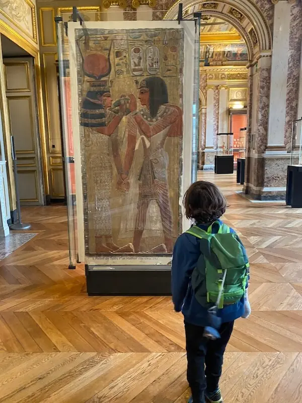 Kind steht im Louvre und betrachtet ein Bild