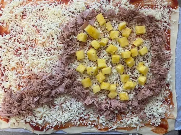 Pizza mit Tunfisch und Ananas als Lupe 