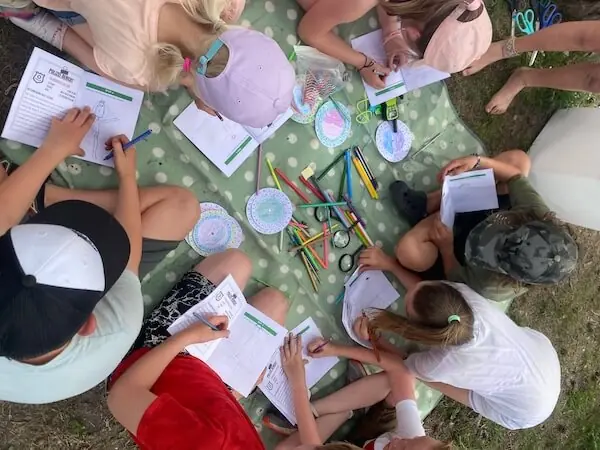 Kinder auf einer Decke, wie sie die Spuren in ihrer Mappe eintragen