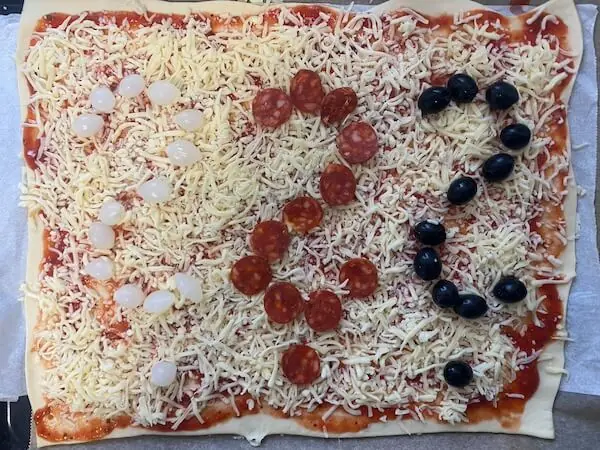 Pizza mit Salami, Silberzweibel und Oliven als 3 Fragezeichen