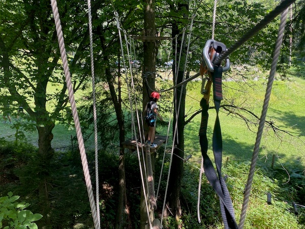 Waldseilpark in Kärnten, Kind auf einem Element mit Helm und Sicherung