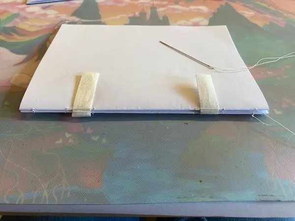 Der Innenteil des Buches mit einer Nadel darauf für die Fadenbindung beim Buch