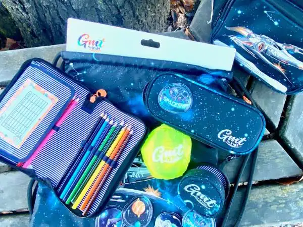 Teile die zur Schultasche gehören auf einer Bank ausgebreitet