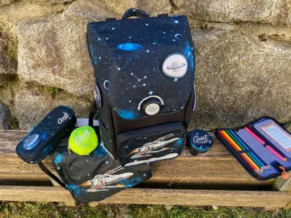 Schultasche auf einer Bank mit allen Teilen die dazu gehören