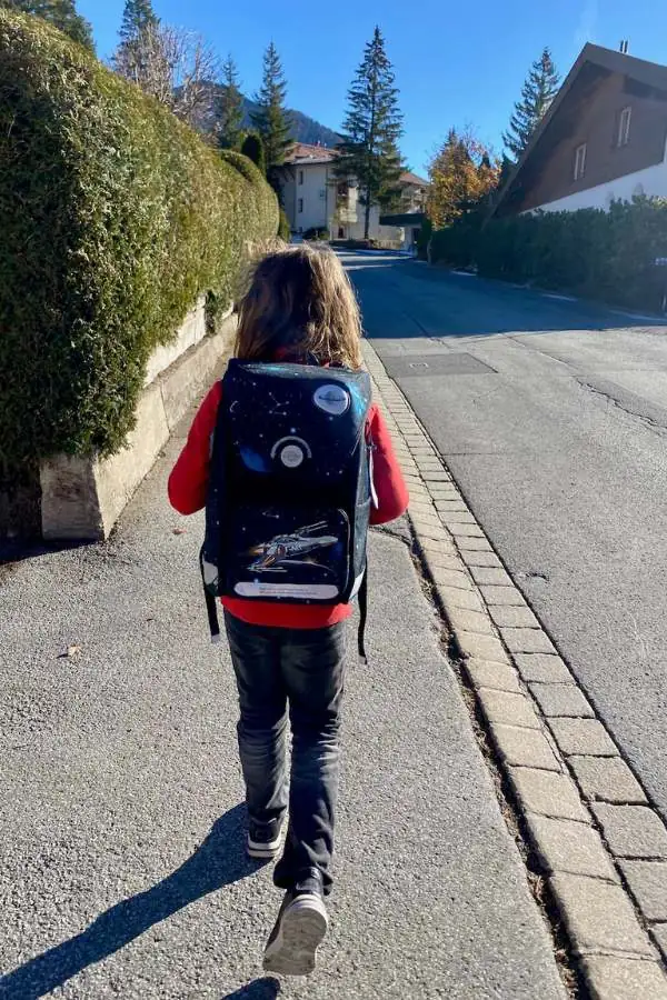 Kind mit Schulranzen am Rücken auf dem Schulweg