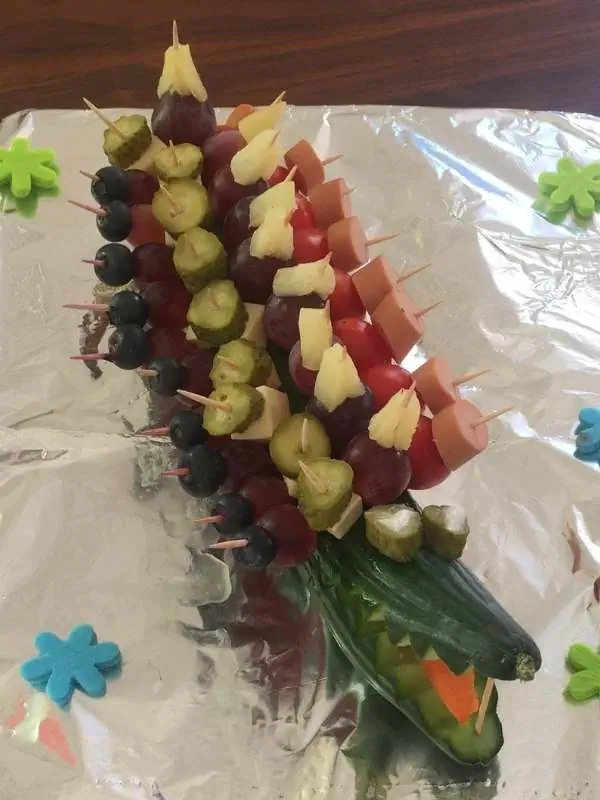 Bunte Obst- und Gemüsespieße mit Trauben, Gurke und Käse, dekoriert für eine Party oder Feier, auf Aluminiumfolie präsentiert, ideal für gesunde Snacks und Kinderfeste.