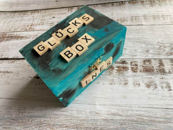 Glücksbox: eine kleine Holzbox mit Acrylfarben grün und schwarz bemalt und mit einzelnen Holzbuchstaben "Glücksbox" beklebt