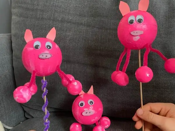 drei Schweinchen aus Styroporkugeln in rosa angemalt auf einem Holzstab