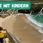 Beitragsbild mit dem Titel: Algarve mit Kindern - Delfine, Klippen und Abenteuer mit einem Strand im Hintergrund mit türkisgrünem Wasser und einem Kind, das gerade die Treppen hinunter geht