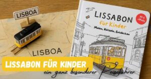 Lissabon Reiseführer für Kinder mit Mal und Rätselaufgaben liegt auf einem Tisch, daneben eine kleine Tram 28 und der Schriftzug Lisboa