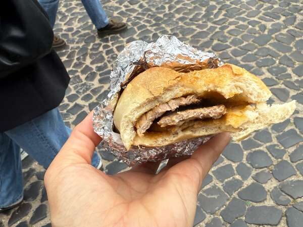 Bifana Sandwich abgebissen in der Hand gehalten