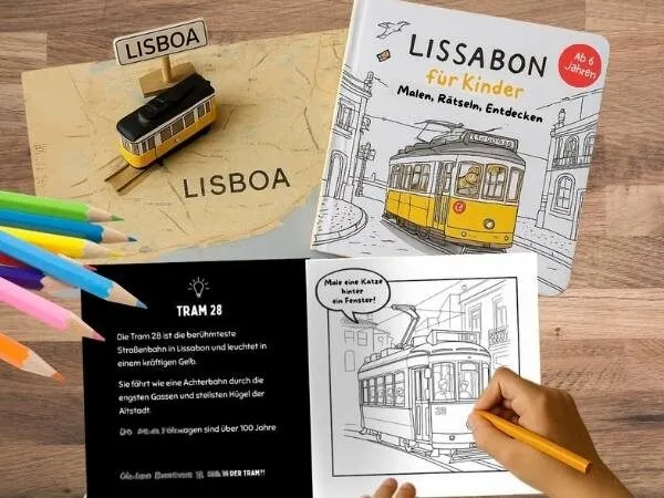 Reiseführer von Lissabon für Kinder ab 6 Jahren liegt rechts oben, links sind Farbstifte und unten malt eine Kinderhand gerade eine Seite im Buch an