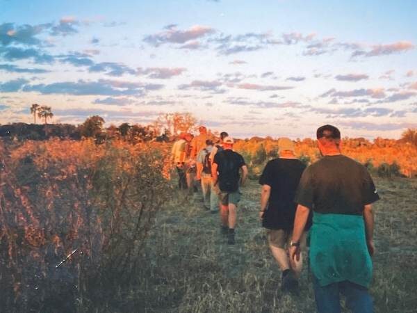 Eine Gruppe Menschen, die in Afrika eine Weg Richtung Sonnenuntergang geht