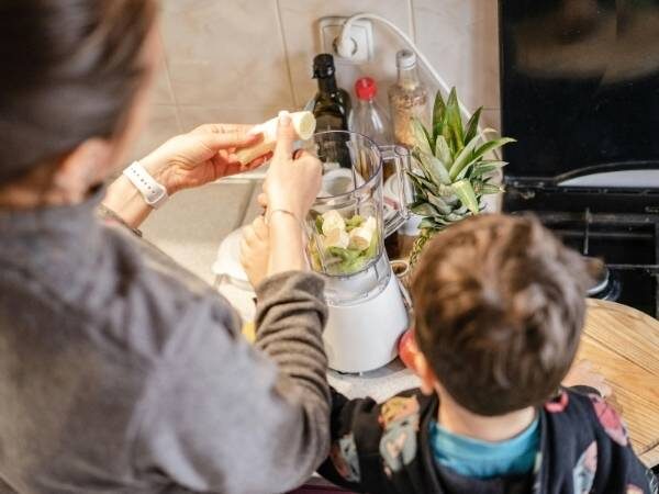 Mama und Kind, die gerade bei einem Mixer ein gesundes Getränk zubereiten