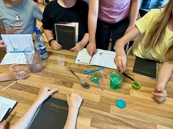 Kinder stehen um einen Tisch mit Materialien darauf für einen Zaubertrank