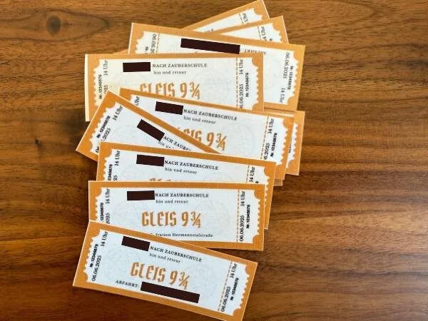 Harry Potter Tickets für den Besuch der Zauberschule auf einer Holztischoberfläche im MamaBlog-Design.
