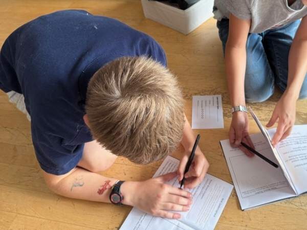 Kinder am Boden, die gerade etwas in die Bücher eintragen