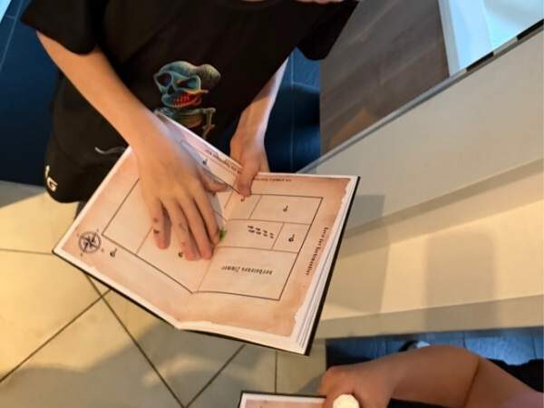 ein offenes Buch mit einem Plan in einer Kinderhand